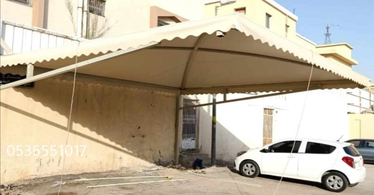 مظلة قماشية ثابتة تغطي موقف سيارة وتوفر حماية من الشمس والأمطار